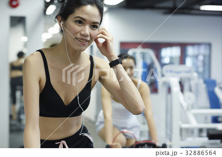 a girl is listening to music and cycling in gym center 32886564