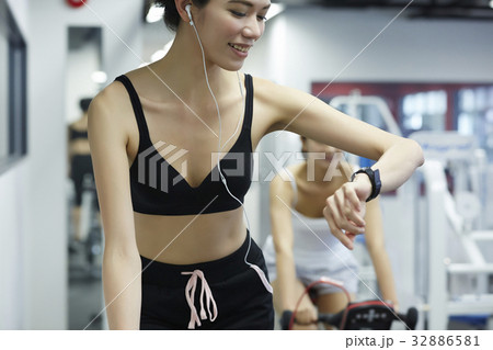 Woman is watching her watch while riding bike in fitness club. Woman is watching her watch while riding bike in fitness club. 32886581