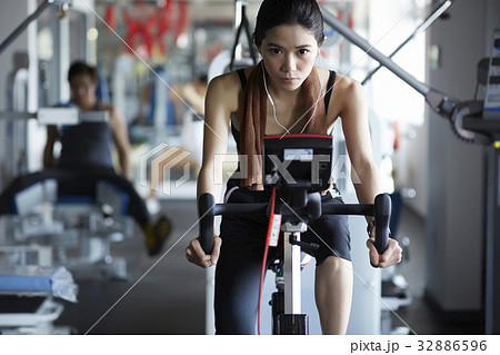 A slim and heathy woman is riding bicycle in the fitness club A slim and heathy woman is riding bicycle in the fitness club 32886596