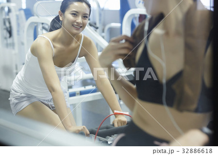 two women are cycling and looking at each other in a gym center two women are cycling and looking at each other in a gym center 32886618