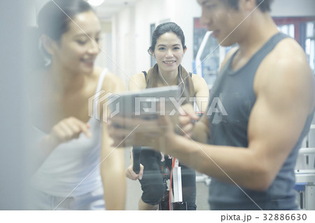 smiling woman is looking at her friend and coach at a fitness club smiling woman is looking at her friend and coach at a fitness club 32886630