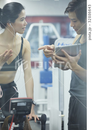A man is training to a woman with a tablet at a fitness center 32886643
