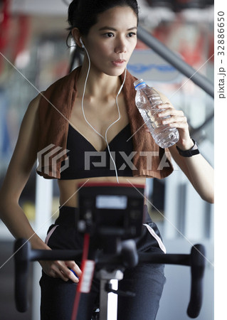 A girl is taking a break after doing exercise and drinking water at fitness center A girl is taking a break after doing exercise and drinking water at fitness center 32886650
