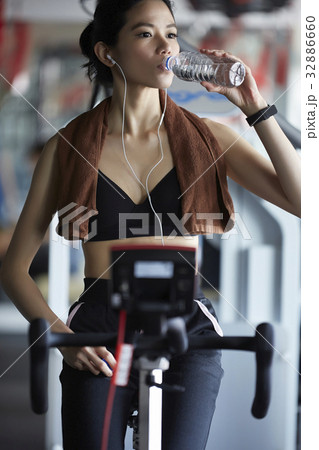 A girl is taking a break and drinking water at fitness center 32886660
