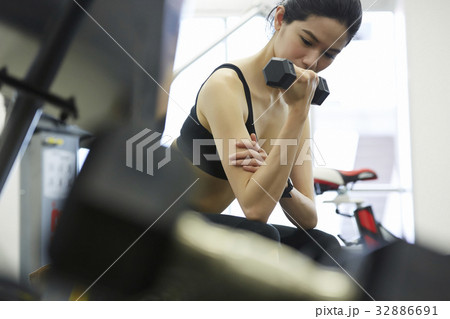 A woman is doing exercise withdumbbell at fitness center 32886691
