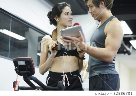 The couple in sportswear is looking together in the gym The couple in sportswear is looking together in the gym 32886701