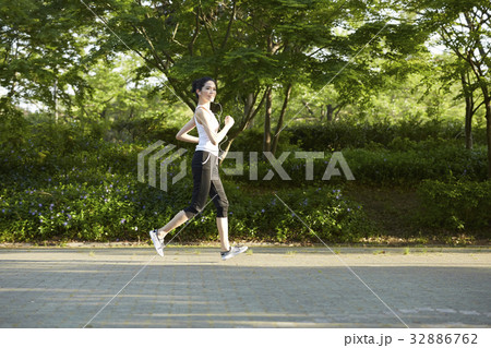 A photo of Thai woman jogging and listening to music outside. 32886762