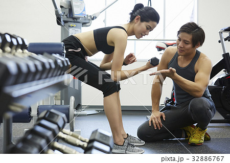 A photo of Thai instructor instructing a women to lift dumbbells in a gym. A photo of Thai instructor instructing a women to lift dumbbells in a gym. 32886767