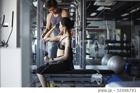 A photo of Thai woman lifting dumbbells with her instructor's help. A photo of Thai woman lifting dumbbells with her instructor's help. 32886781