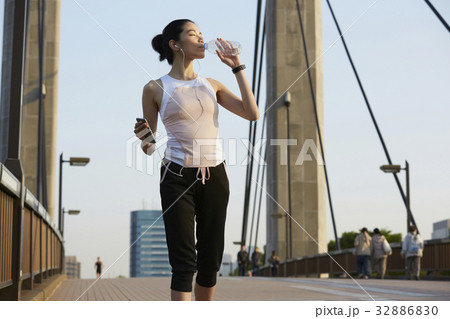 a photo of a woman drinking water while holding her phone. 32886830