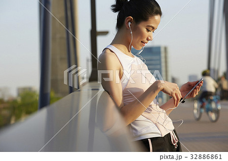 a woman in sportswear is standing and using her phone a woman in sportswear is standing and using her phone 32886861