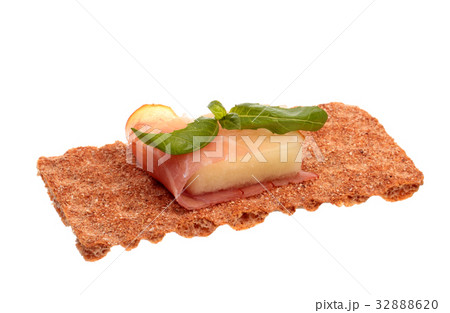 Parma ham with melon and basil on a rye crisp 32888620