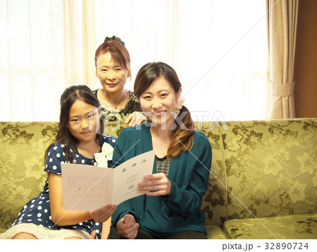 女子児童と「あゆみ」（通信簿）を見る、お母さんとおばあさん。（校章、校訓は実在しない架空のダミー） 32890724