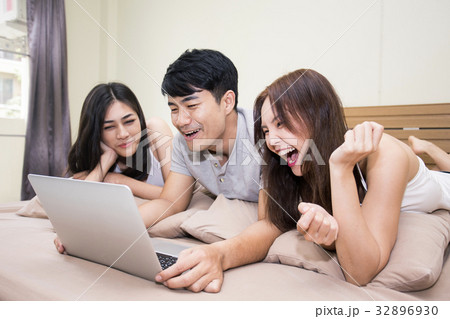 Asian man and woman using computer on bed 32896930