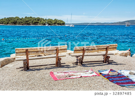 Wooden benches and towels on beach, Solta, Croatia 32897485