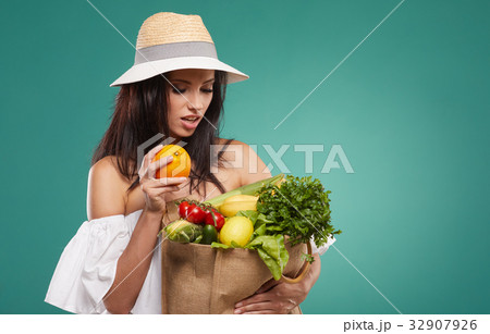woman holding a grocery bag full of fresh and healthy food isolated on green background woman holding a grocery bag full of fresh and healthy food isolated on green background 32907926