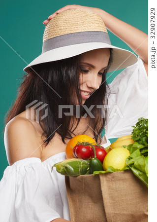 woman holding a grocery bag full of fresh and healthy food isolated on green background woman holding a grocery bag full of fresh and healthy food isolated on green background 32907929