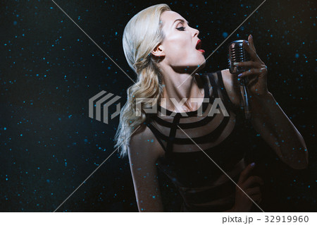 The singer is on stage with a microphone. 32919960