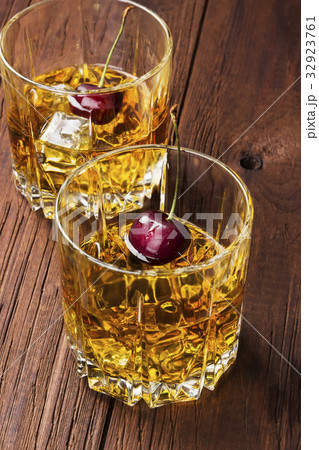 Cocktail from whisky with cherry in two glasses Cocktail from whisky with cherry in two glasses 32923761