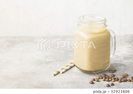 Milk pouring in ice coffee in a tall glass Milk pouring in ice coffee in a tall glass 32923806