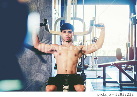 Fitness man exercising at the gym on a machine Fitness man exercising at the gym on a machine 32932238