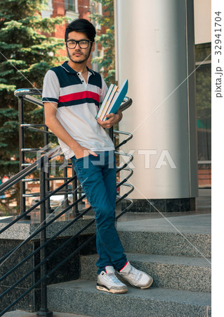 trendy guy stands on the street and holding a book 32941704
