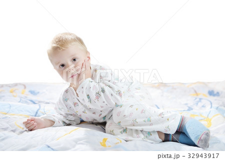 Funny cute little child in pyjamas with blonde hair lies on a bed 32943917