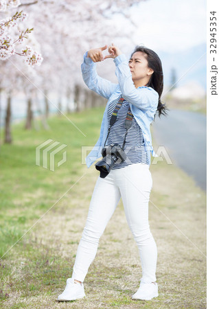 満開の桜と女性カメラマン 32945354