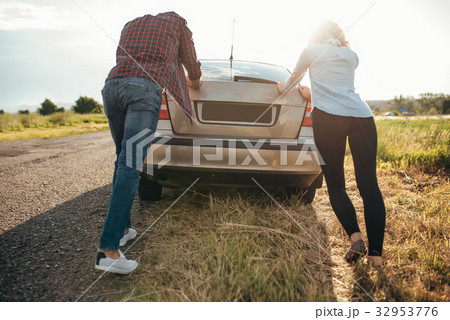 Man and woman pushing a broken car, back view Man and woman pushing a broken car, back view 32953776