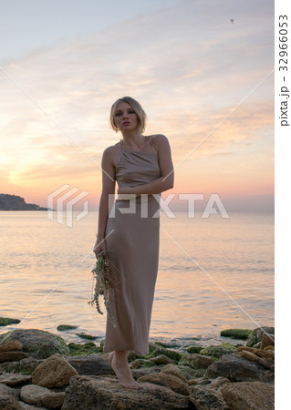 Beautiful young model in a long dress on the coast Beautiful young model in a long dress on the coast 32966053