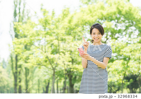 携帯電話を持つ女性(緑背景) 携帯電話を持つ女性(緑背景) 32968334