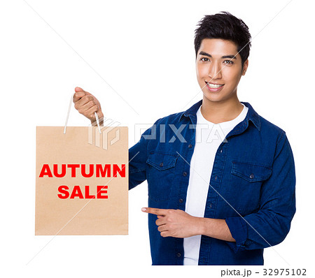Man finger point to shopping bag for showing phrase of autumn sale 32975102