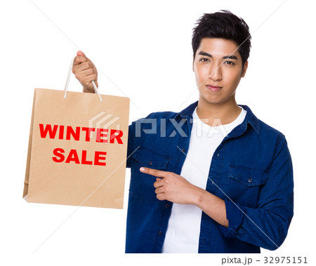 Asian mixed Indian man finger point to shopping bag for showing phrase of winter sale Asian mixed Indian man finger point to shopping bag for showing phrase of winter sale 32975151