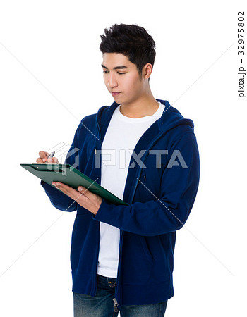 Asian young man take note on clipboard Asian young man take note on clipboard 32975802