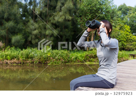 Asian woman watching though binoculars and sitting besides revier 32975923