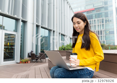 Asian Woman look at the laptop computer and holding a coffee cup 32976026