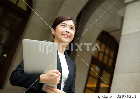 Businesswoman holding laptop computer at outdoor Businesswoman holding laptop computer at outdoor 32976211