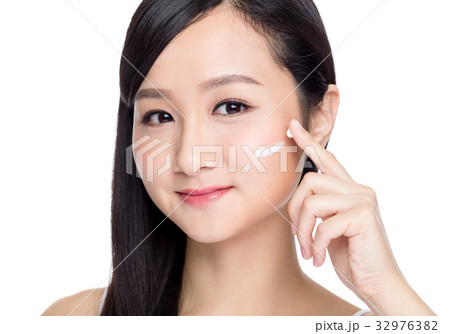 Woman applying cosmetic cream on her face 32976382
