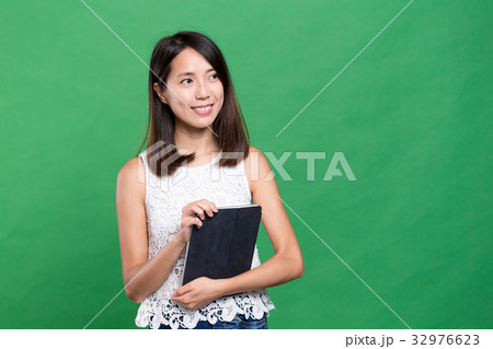 Woman holding tablet computer and looking far away Woman holding tablet computer and looking far away 32976623