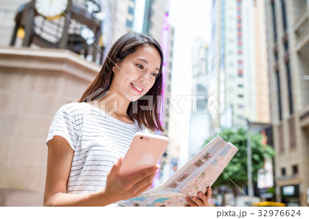Woman using city map and cellphone 32976624