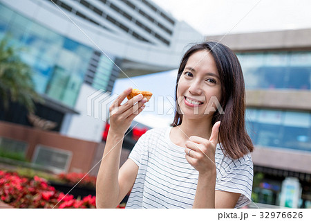 Woman having egg tart and showing thumb up 32976626