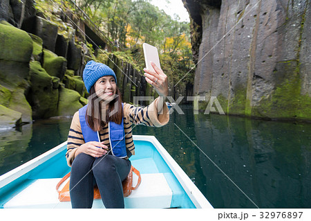 Woman taking photo by mobile phone and sitting on boat at Takachiho gorge 32976897