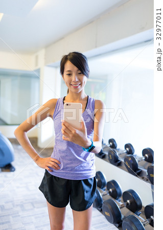 Woman taking selfie in front of mirror in gym Woman taking selfie in front of mirror in gym 32977011