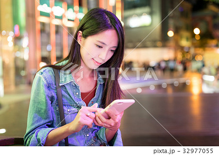 Woman use of smart phone in the city at night Woman use of smart phone in the city at night 32977055
