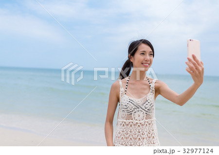 Woman taking selfie by mobile phone with the sea 32977124