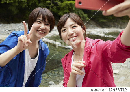 河原で記念撮影をする女性 32988539