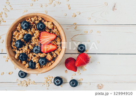 Homemade granola and fresh berries on wood table Homemade granola and fresh berries on wood table 32994910