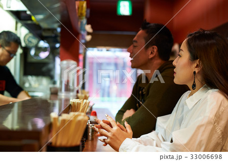 A couple is looking at something at a ramen restaurant 33006698