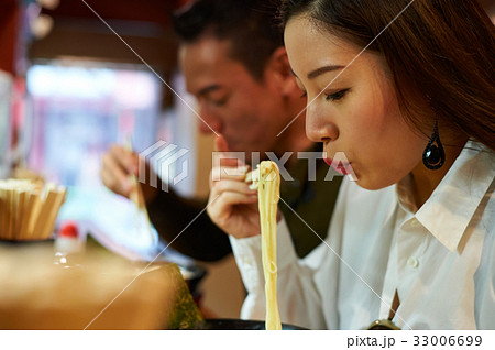 A woman is blowing on ramen at a restaurant. 33006699