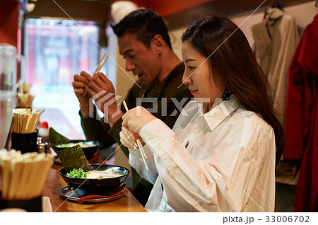 A couple is holding their chopsticks and looking at food. A couple is holding their chopsticks and looking at food. 33006702